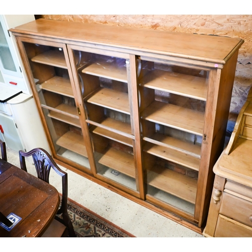 450 - An old pine and beech library bookcase upper part, with three twin glazed panel sliding doors enclos... 