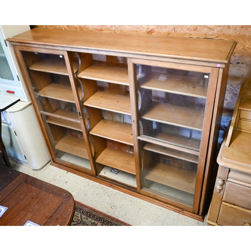 450 - An old pine and beech library bookcase upper part, with three twin glazed panel sliding doors enclos... 