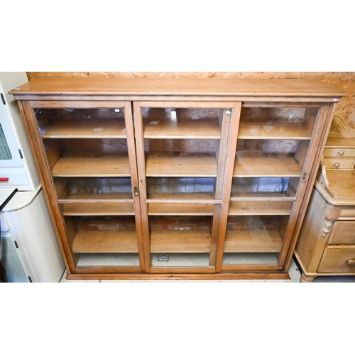 450 - An old pine and beech library bookcase upper part, with three twin glazed panel sliding doors enclos... 