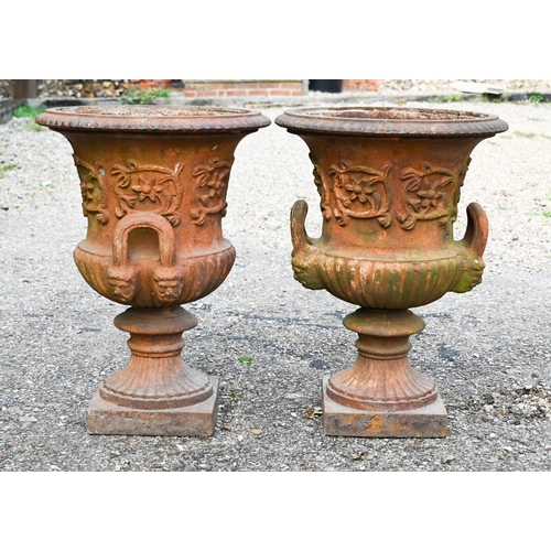 5 - A pair of old weathered cast iron campagna urns, with twin handles raised on square pedestal bases, ... 