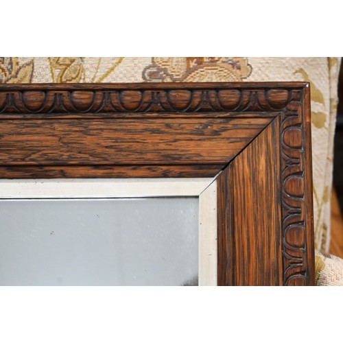 497 - A carved oak mirror in the Arts & Crafts manner