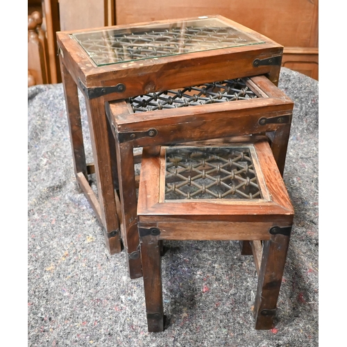 105 - A trio of Indian hardwood nest of tables with iron grilled top under glass, the largest 44.5 x 30 x ... 