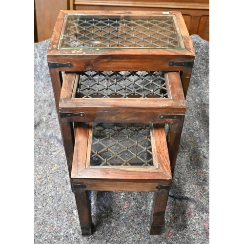 105 - A trio of Indian hardwood nest of tables with iron grilled top under glass, the largest 44.5 x 30 x ... 