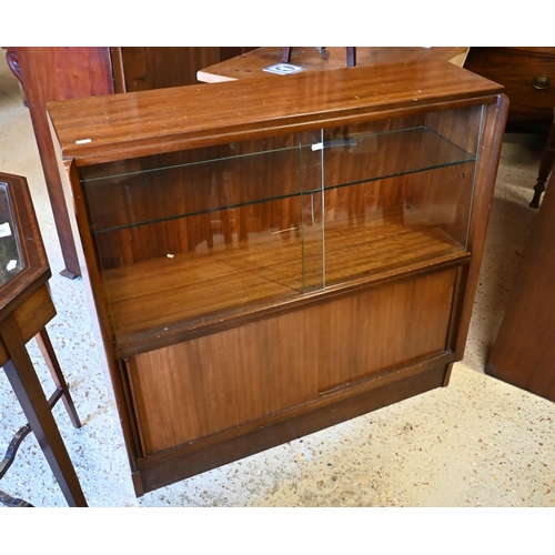 135 - # A companion pair of mid-century slope fronted teak cabinets with glass sliding doors, one with cup... 