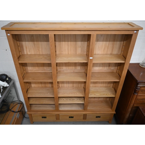 33 - A modern oak open bookcase with adjustable shelves on three drawer base, 186 cm wide x 34 cm deep x ... 