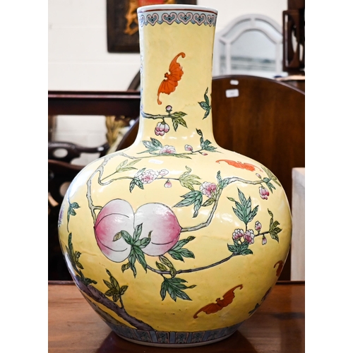 397 - A large Chinese porcelain bottle vase, painted with peaches, flowering prunus and bats, on a yellow ... 