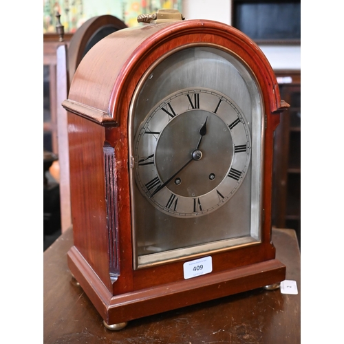 409 - A mahogany-cased mantel clock with arched and silvered dial, brass loop top handle and bun feet, str... 