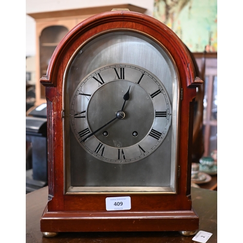 409 - A mahogany-cased mantel clock with arched and silvered dial, brass loop top handle and bun feet, str... 