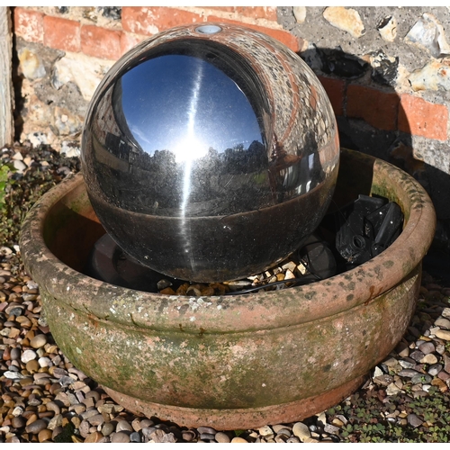 429 - A contemporary stainless steel solar panelled spherical water feature in weathered terracotta bowl