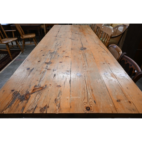 51 - A substantial waxed pine refectory dining table with four-plank rectangular top on twin trestle supp... 