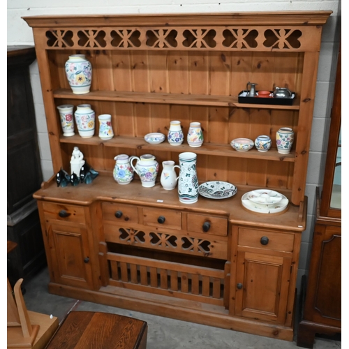 70 - A waxed pine kitchen dresser, the two shelf plate rack on inverted breakfront base with drawers and ... 