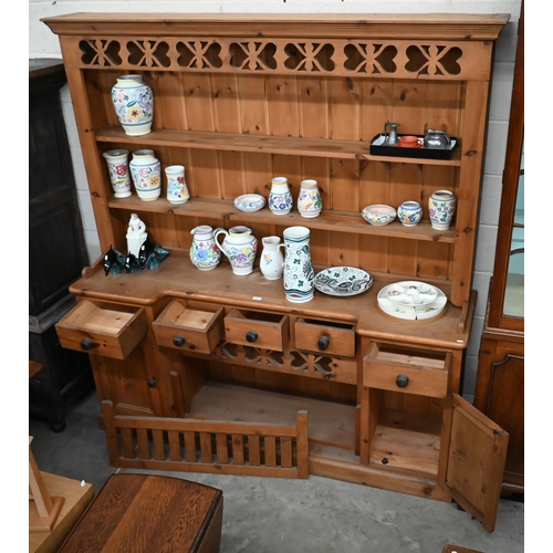 70 - A waxed pine kitchen dresser, the two shelf plate rack on inverted breakfront base with drawers and ... 