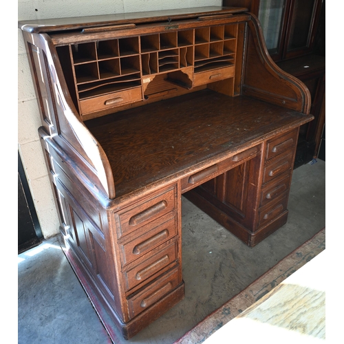 73 - An early 20th century oak roll-top desk, the sliding tambour panel enclosing a fitted interior over ... 