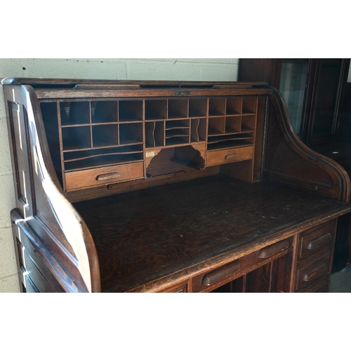 73 - An early 20th century oak roll-top desk, the sliding tambour panel enclosing a fitted interior over ... 