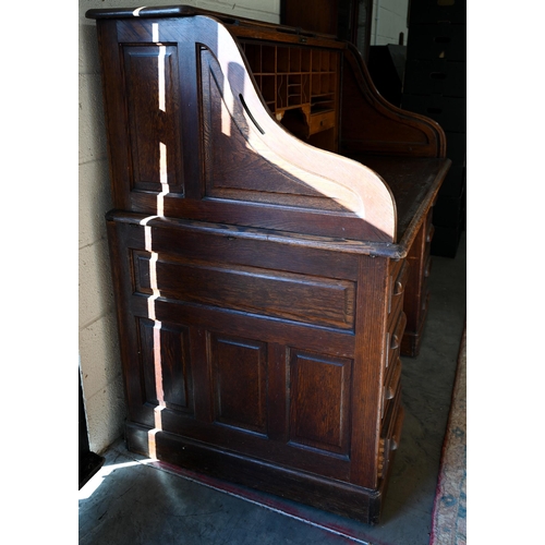 73 - An early 20th century oak roll-top desk, the sliding tambour panel enclosing a fitted interior over ... 