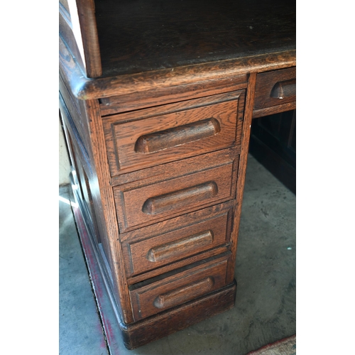 73 - An early 20th century oak roll-top desk, the sliding tambour panel enclosing a fitted interior over ... 