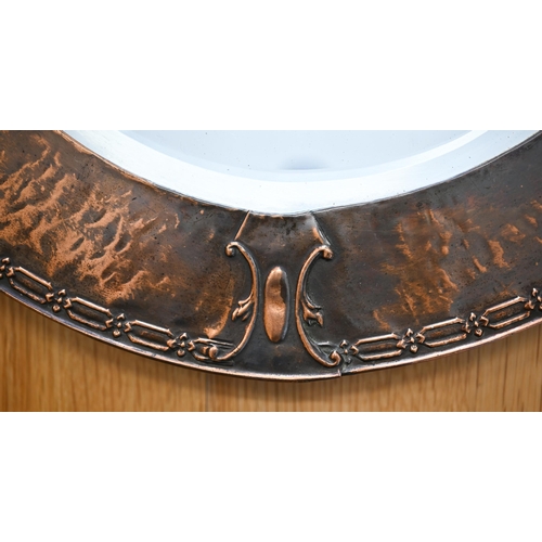 78 - An Arts & Crafts bevelled oval mirror in embossed copper frame, 72 cm wide x 50 cm high