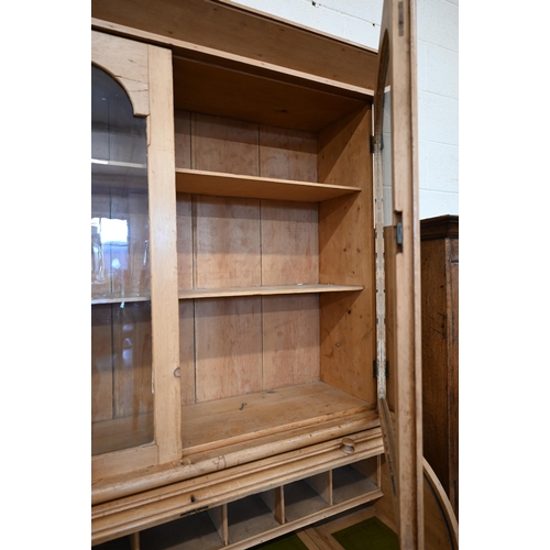 84 - A pine roll-top desk bookcase, pair of glazed doors over sliding tambour panel enclosing fitted inte... 