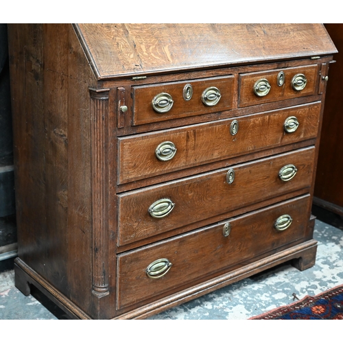 870 - An 18th century oak bureau cabinet, the upper part with pair of panelled doors enclosing shelves, th... 