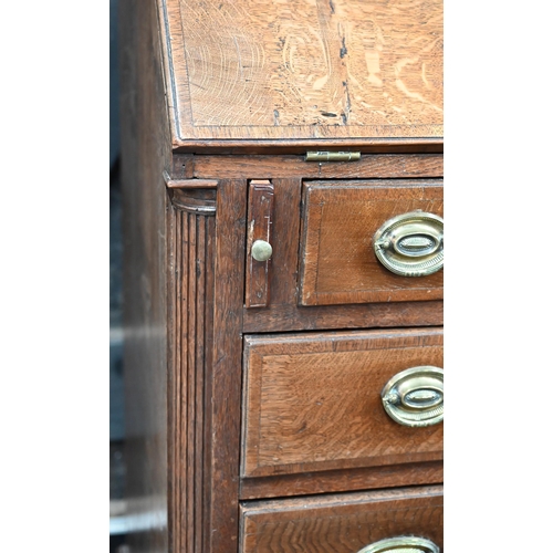 870 - An 18th century oak bureau cabinet, the upper part with pair of panelled doors enclosing shelves, th... 