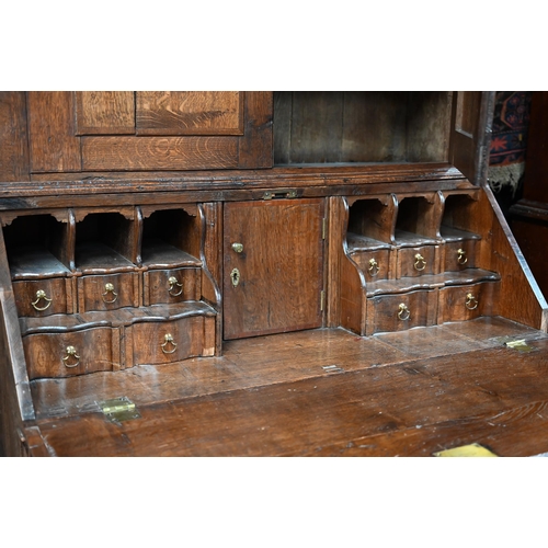 870 - An 18th century oak bureau cabinet, the upper part with pair of panelled doors enclosing shelves, th... 