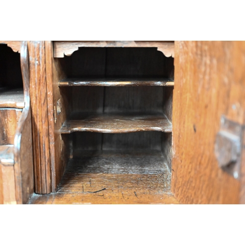 870 - An 18th century oak bureau cabinet, the upper part with pair of panelled doors enclosing shelves, th... 