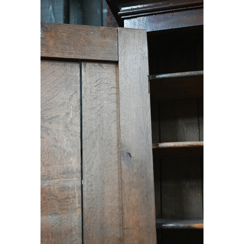 870 - An 18th century oak bureau cabinet, the upper part with pair of panelled doors enclosing shelves, th... 