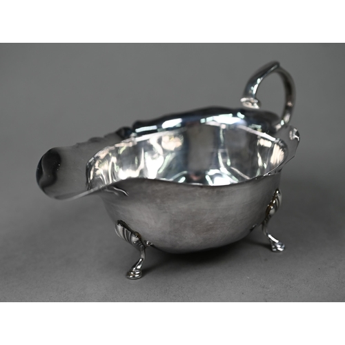 123 - A silver sauce boat in the Georgian manner, with cut rim, scroll handle and hoof feet, Birmingham 19... 