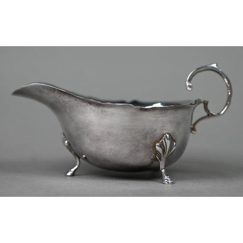 123 - A silver sauce boat in the Georgian manner, with cut rim, scroll handle and hoof feet, Birmingham 19... 