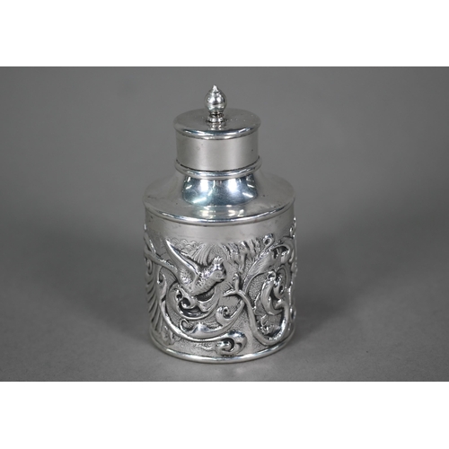 191 - An Edwardian cylindrical silver tea caddy and cover, ornately embossed with exotic birds, snakes and... 