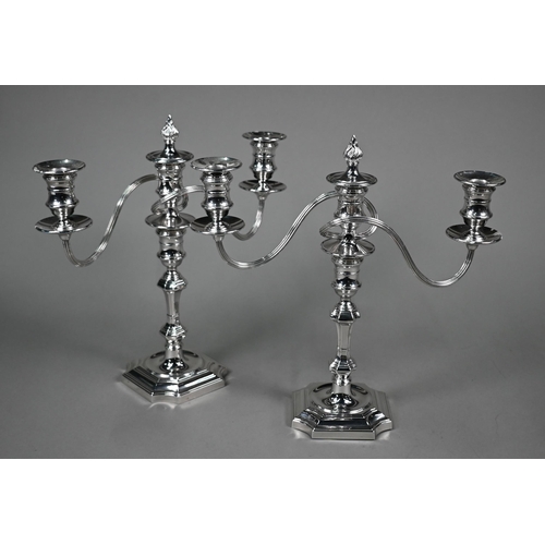 21 - A pair of twin branch candelabra in the early Georgian manner, with twin sconces and flame finials, ... 