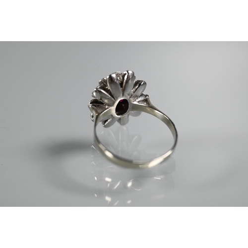 224 - A vintage cluster ring in the form of a flower set with rubies, size Q, 2cm diam