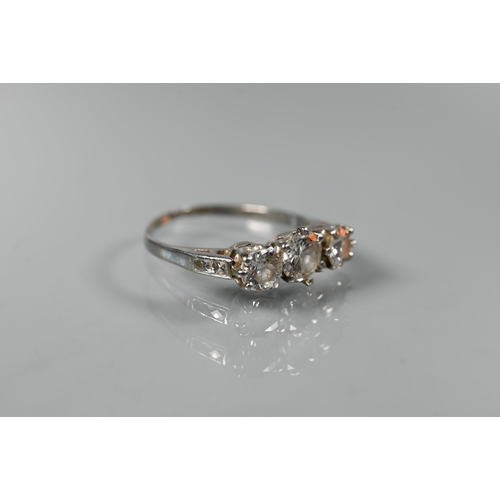 225 - A diamond ring, the three graduated diamonds claw set with diamond set shoulders, white metal set st... 