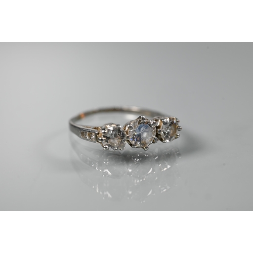 225 - A diamond ring, the three graduated diamonds claw set with diamond set shoulders, white metal set st... 