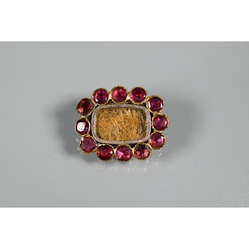 228 - A Georgian gold garnet and hairwork mourning brooch with central hairwork panel and flat-top garnet ... 