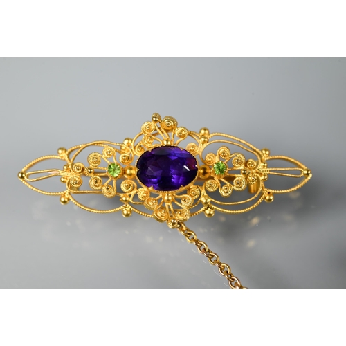 234 - A Victorian 15ct gold brooch of open scroll form, set central oval purple stone with two peridot to ... 