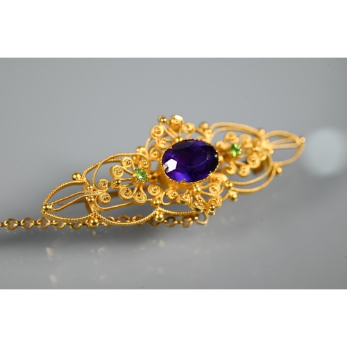 234 - A Victorian 15ct gold brooch of open scroll form, set central oval purple stone with two peridot to ... 