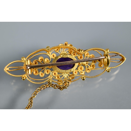 234 - A Victorian 15ct gold brooch of open scroll form, set central oval purple stone with two peridot to ... 