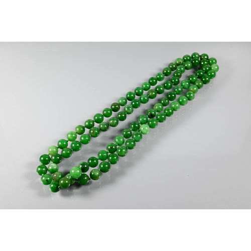 279 - WITHDRAWN A row of uniform round jade beads, varying hues of green, double knotted throughout, 60 cm... 