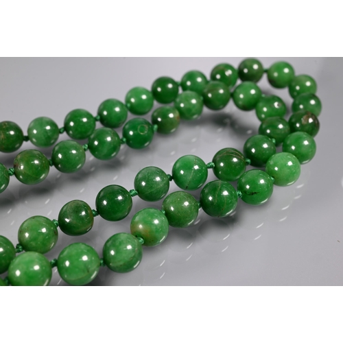 279 - WITHDRAWN A row of uniform round jade beads, varying hues of green, double knotted throughout, 60 cm... 