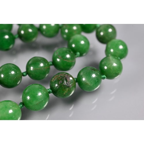 279 - WITHDRAWN A row of uniform round jade beads, varying hues of green, double knotted throughout, 60 cm... 