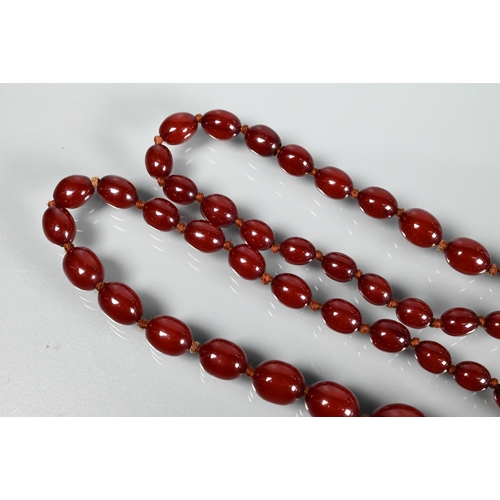 297 - A facetted orange amber graduated necklace, 54.1g; a cherry red amber graduated necklace, 50.4g; a r... 