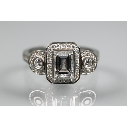 305 - An Art Deco style diamond-set cluster ring, the central rectangular diamond flanked by a collet set ... 