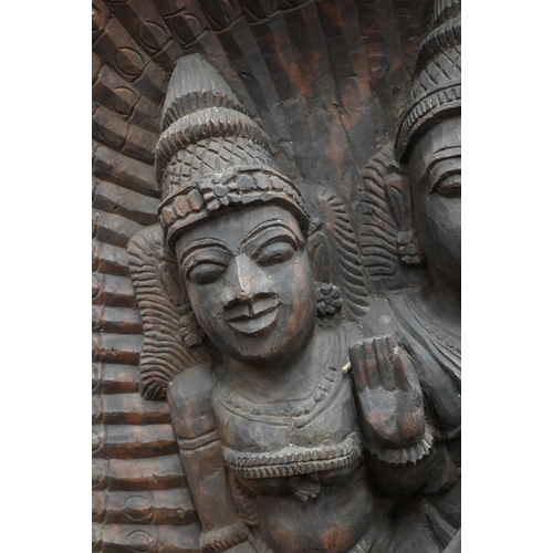 566 - An Indian high-relief carved hardwood panel depicting Karkikeya (Hindu God of War) and his two conso... 