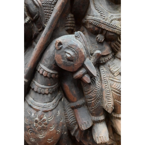 566 - An Indian high-relief carved hardwood panel depicting Karkikeya (Hindu God of War) and his two conso... 