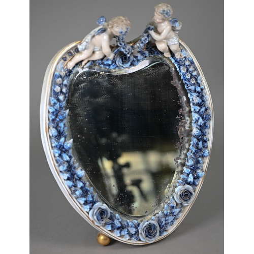 671 - An antique Sitzendorf porcelain heart-shaped mirror surmouted by two cherubs, on floral-encrusted fr... 