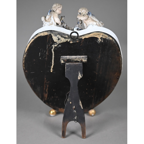 671 - An antique Sitzendorf porcelain heart-shaped mirror surmouted by two cherubs, on floral-encrusted fr... 