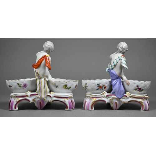 674 - Two 19th century Berlin porcelain double salts, modelled as putti, their baskets painted with courti... 