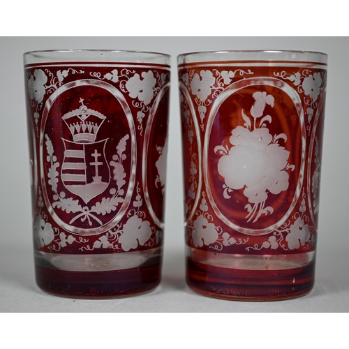 687 - A pair of 19th century German ruby flash glass beakers, cut and etched with armorials, floral sprays... 