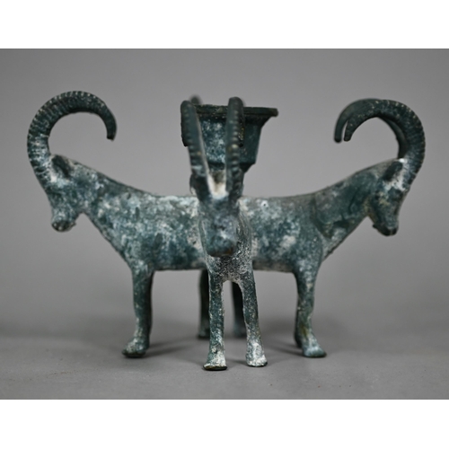 1099 - A verdigris-patinated candlestick supported by four goats, in the antique manner, 11 cm high